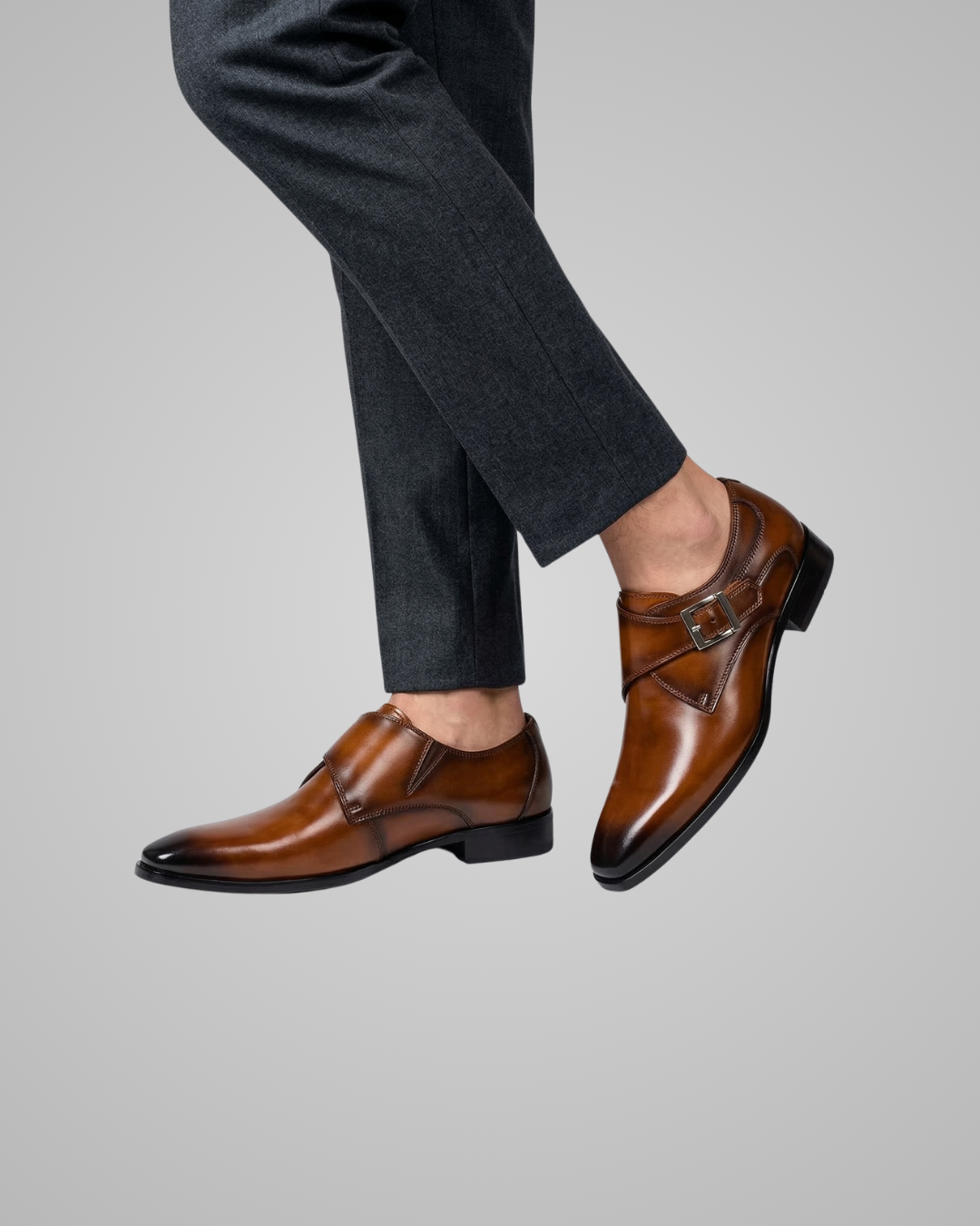 Brown dress shoes worn with dark gray pants on a light gray background