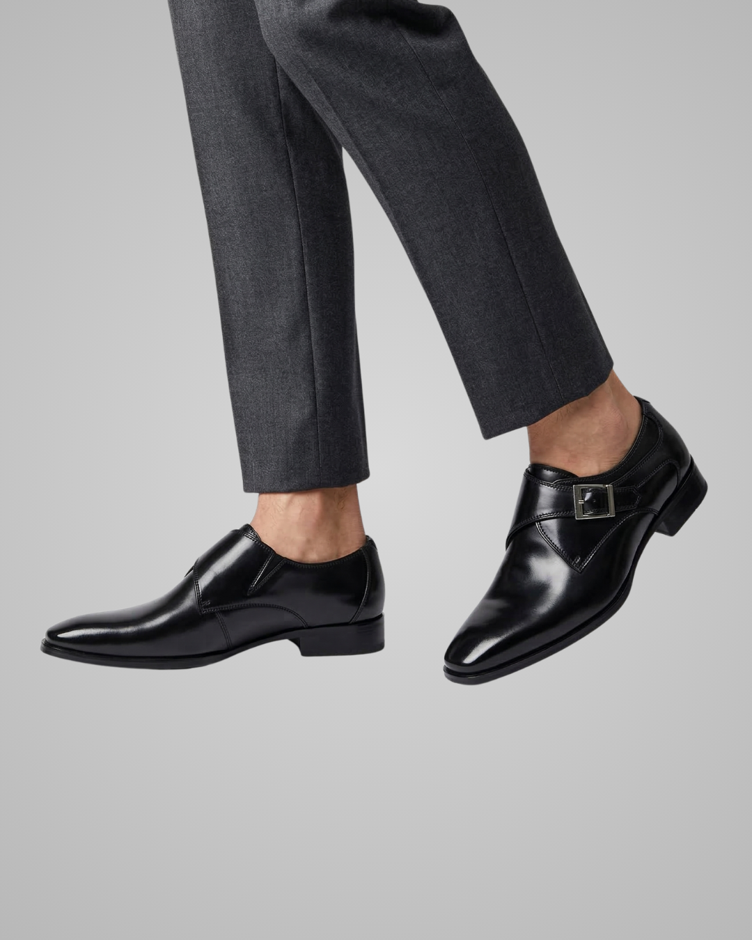 Black dress shoes worn with gray pants on a light gray background