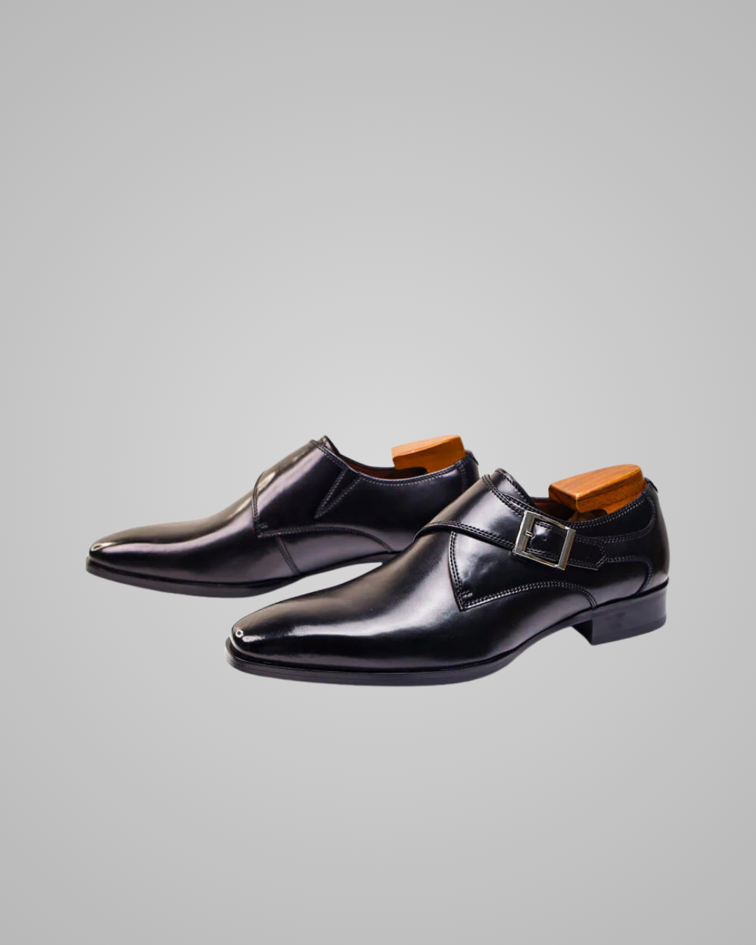 Pair of black dress shoes with brown soles on a light gray background