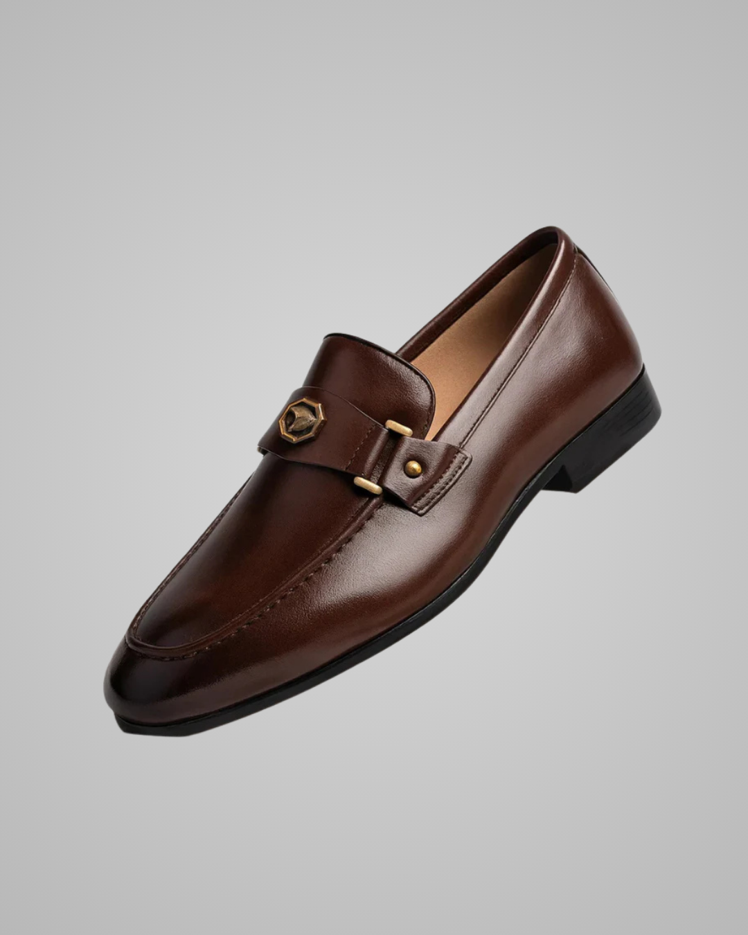 Brown leather loafer with gold buckle on a gray background