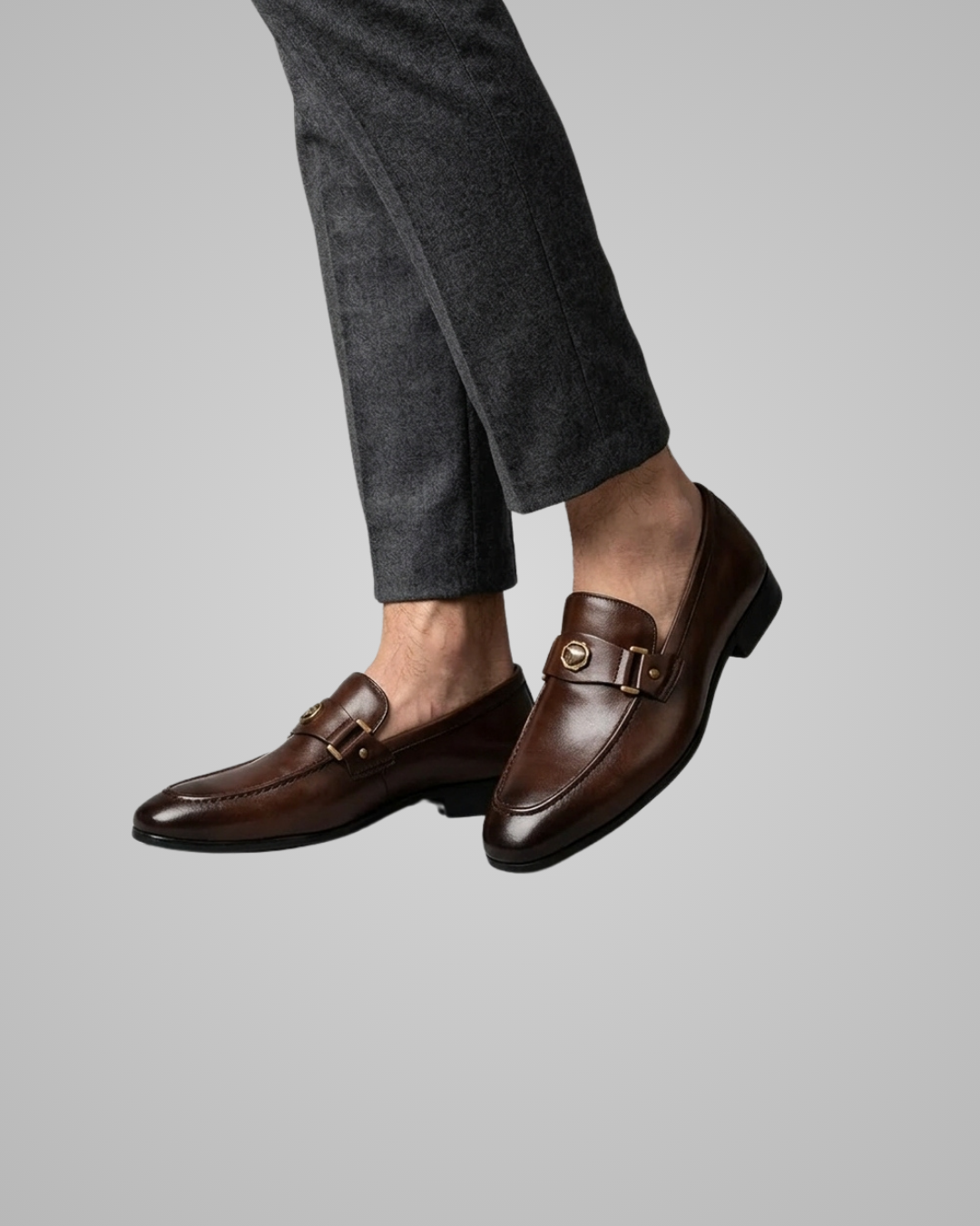 Brown loafers worn with gray pants on a light gray background