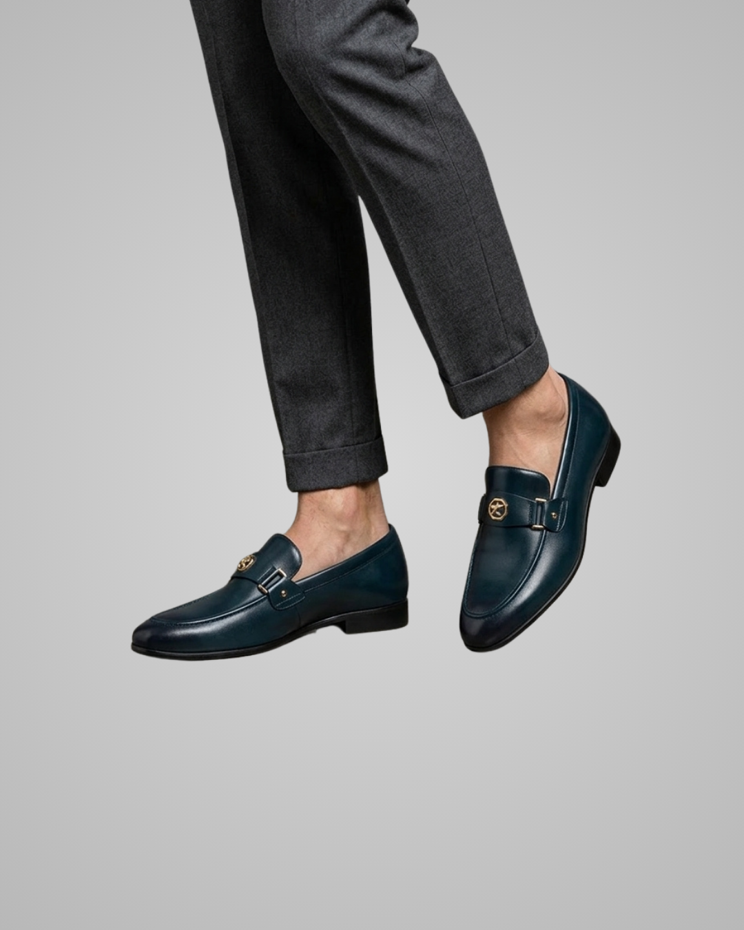 Navy loafers worn with dark gray pants on a light gray background