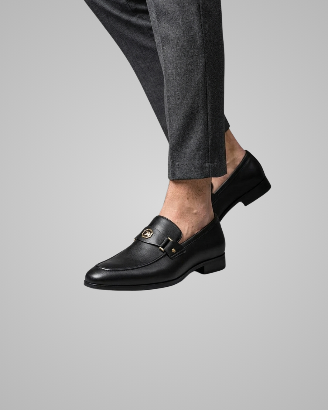 Black loafers worn with gray pants on a light gray background