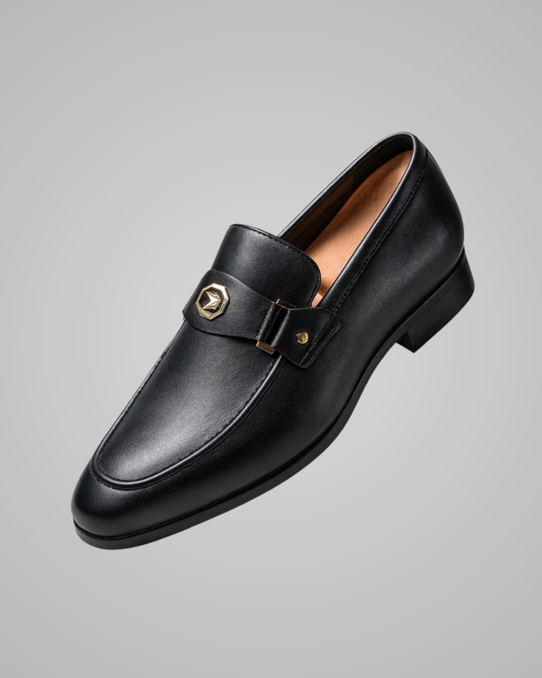 Black leather loafer with gold buckle on a gray background