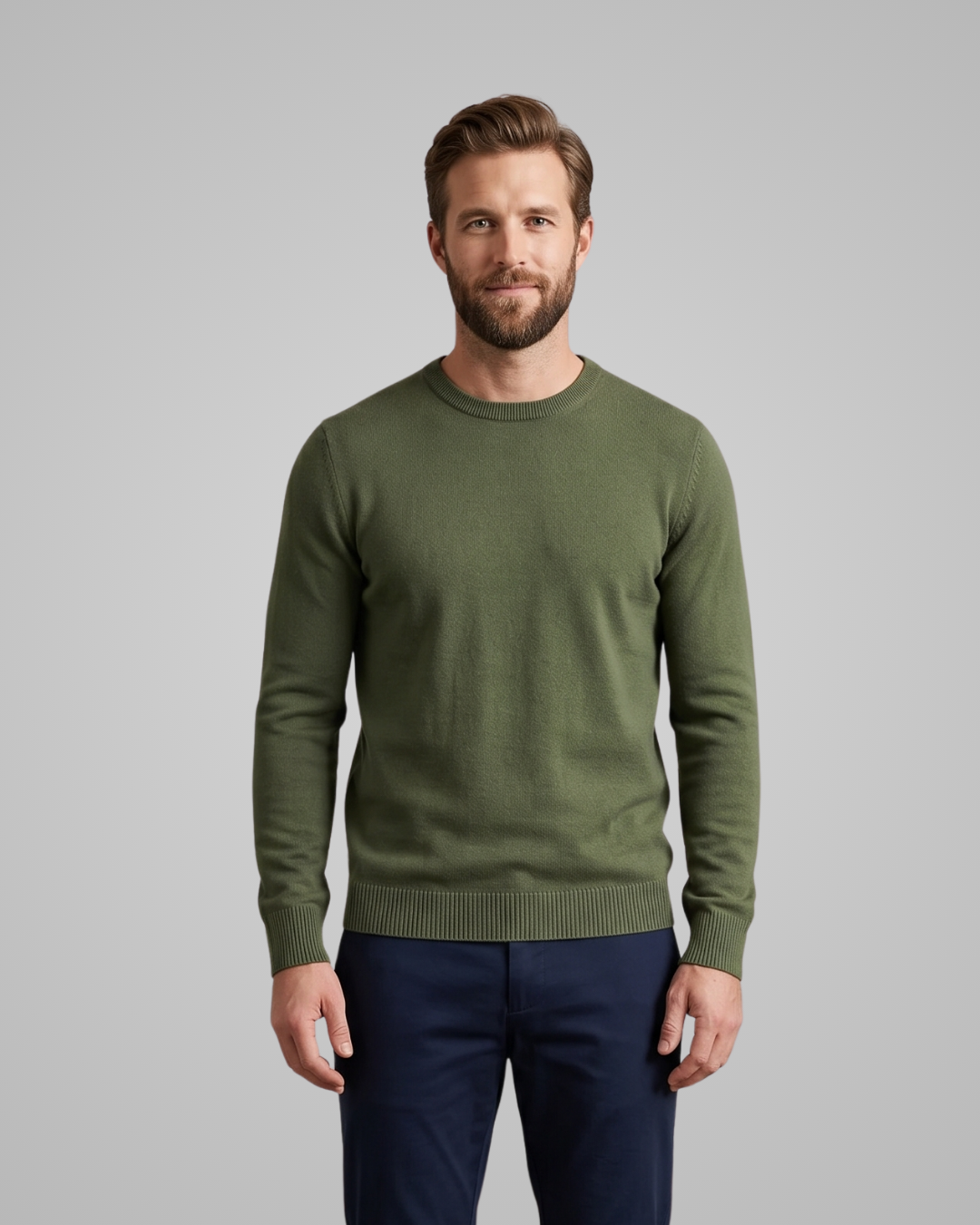 Man wearing a green sweater and navy pants on a gray background