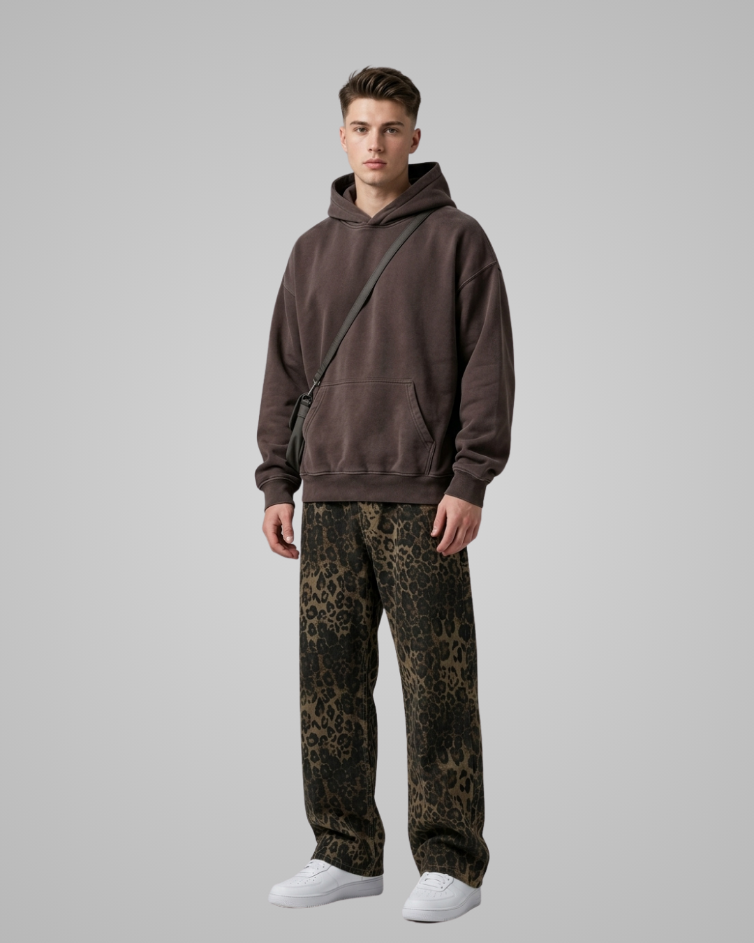 Man wearing a brown hoodie and leopard print pants on a gray background