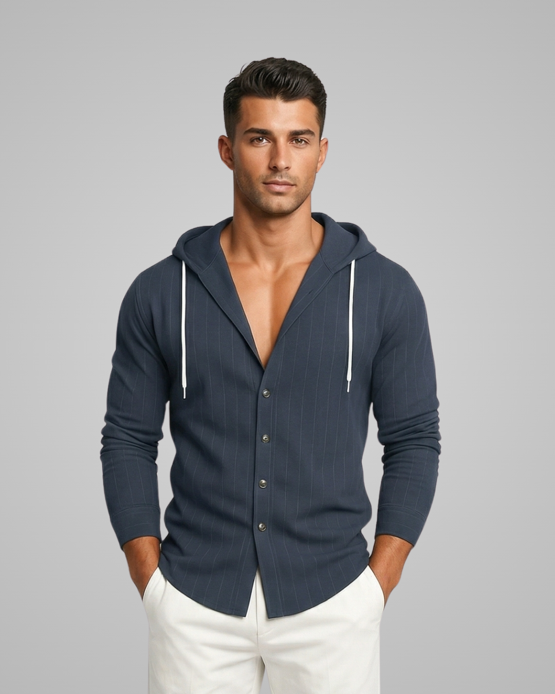 Man wearing a navy blue hooded shirt with white pants on a gray background