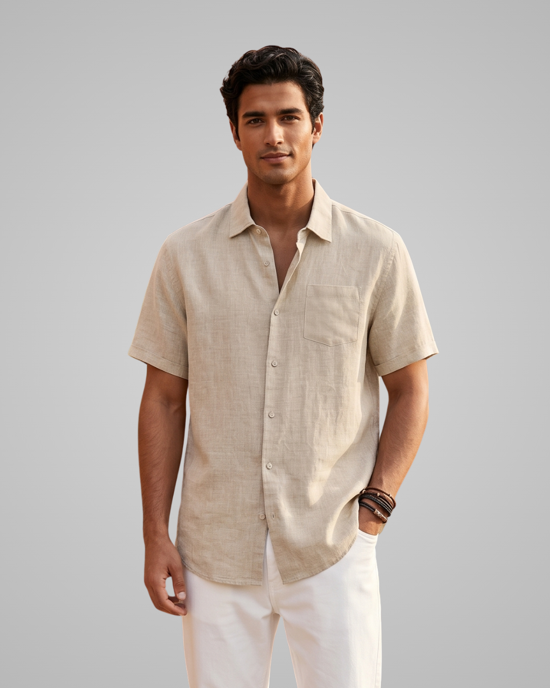 Man wearing a beige short-sleeve shirt and white pants against a gray background