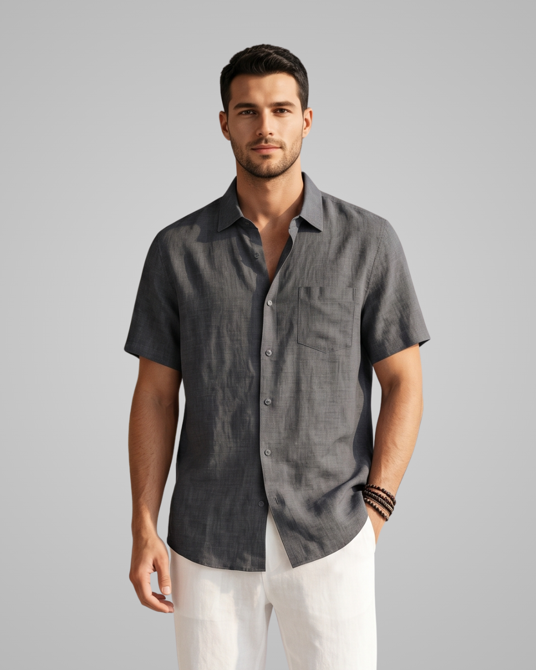 Man wearing a gray short-sleeve shirt and white pants on a gray background