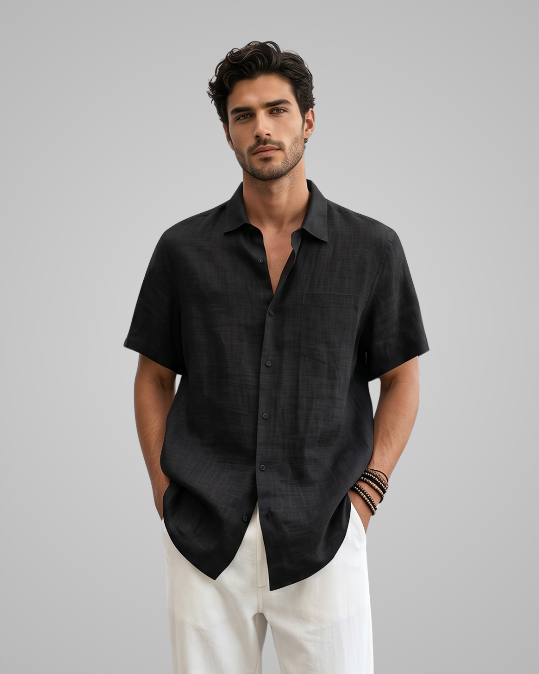 Man wearing a black short-sleeve shirt and white pants on a gray background