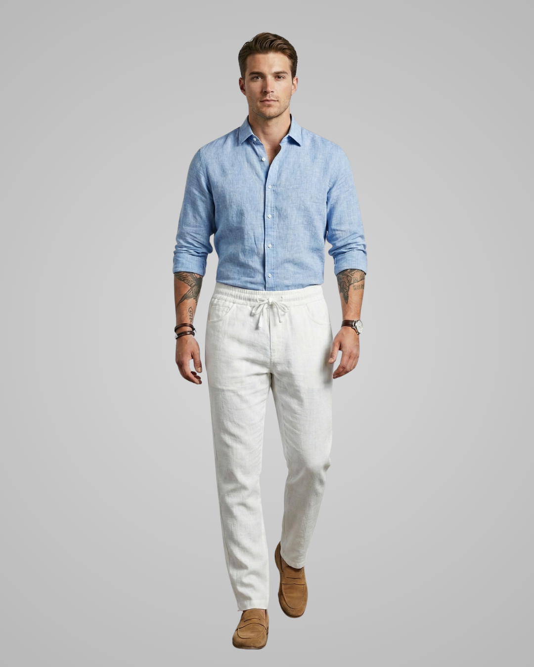 Man wearing a light blue shirt and white pants on a gray background
