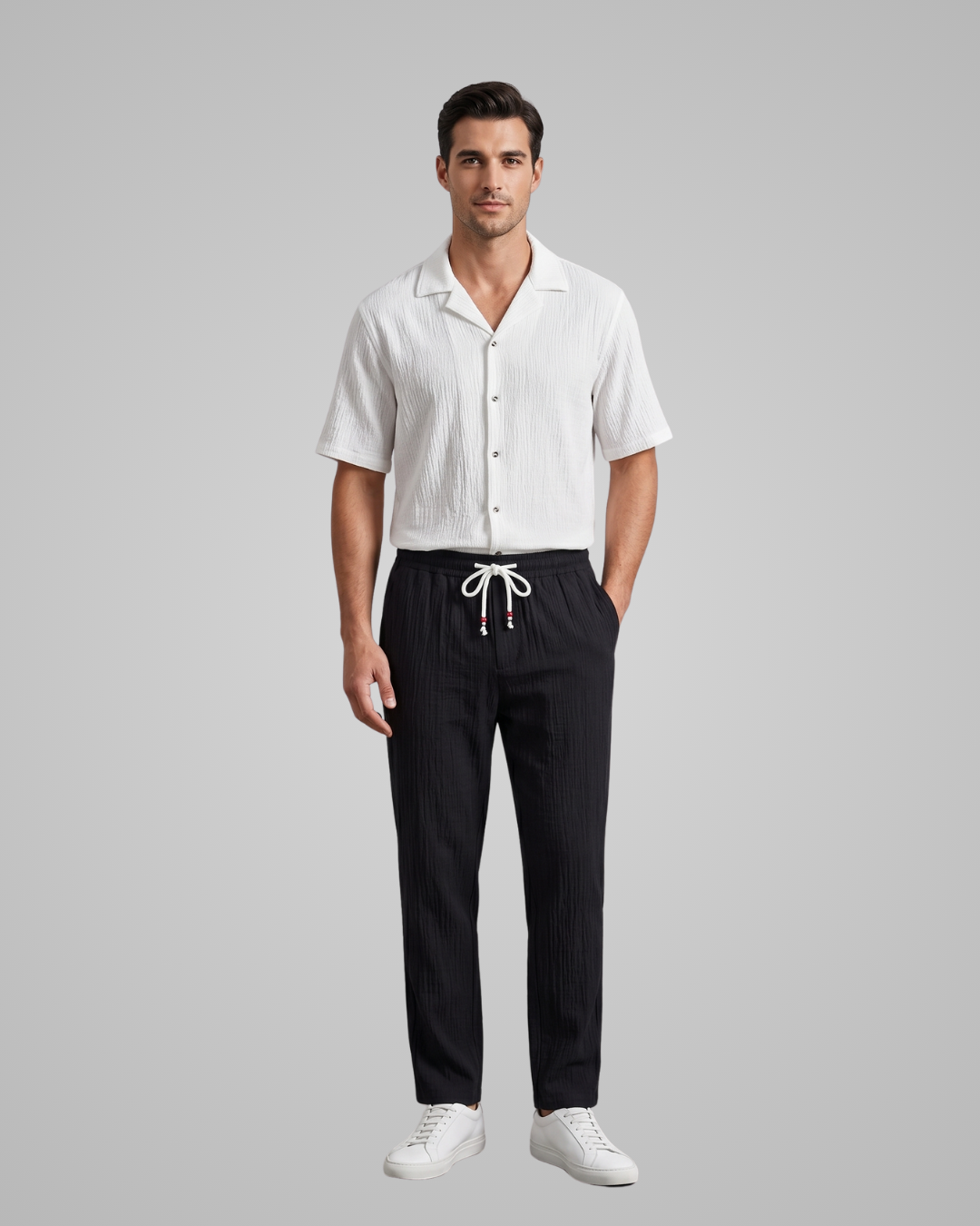 Man wearing a white shirt and black pants on a gray background