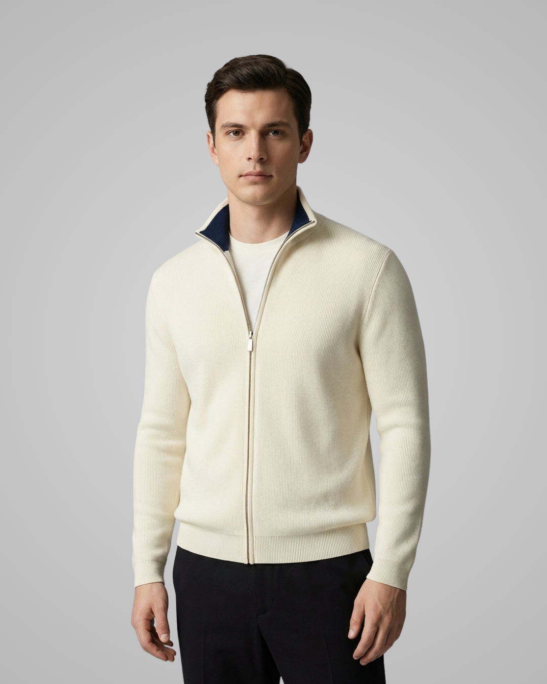 Man wearing a cream-colored zip-up sweater against a gray background