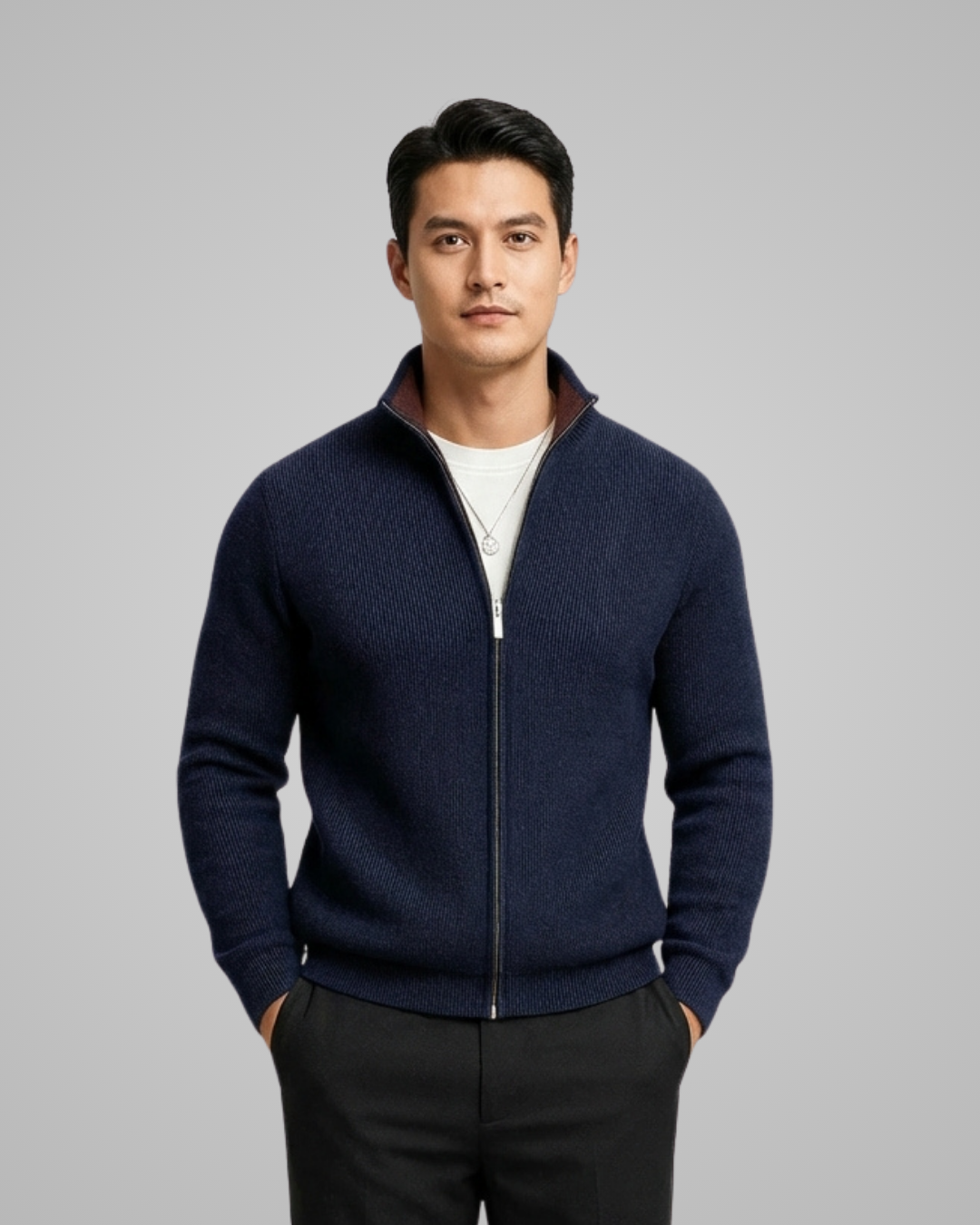 Man wearing a navy blue zip-up sweater over a white shirt on a gray background