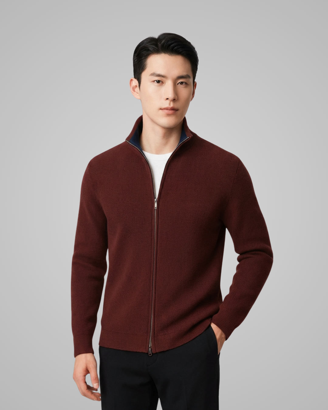 Man wearing a burgundy zip-up sweater on a gray background