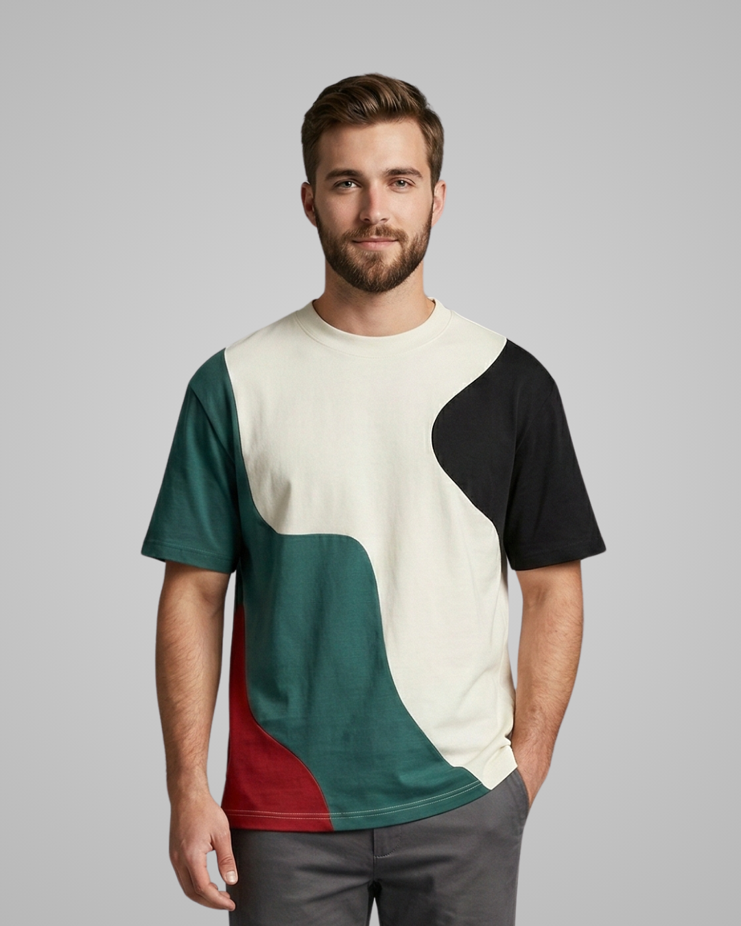 Man wearing a color-blocked t-shirt with green, red, and black design on a gray background