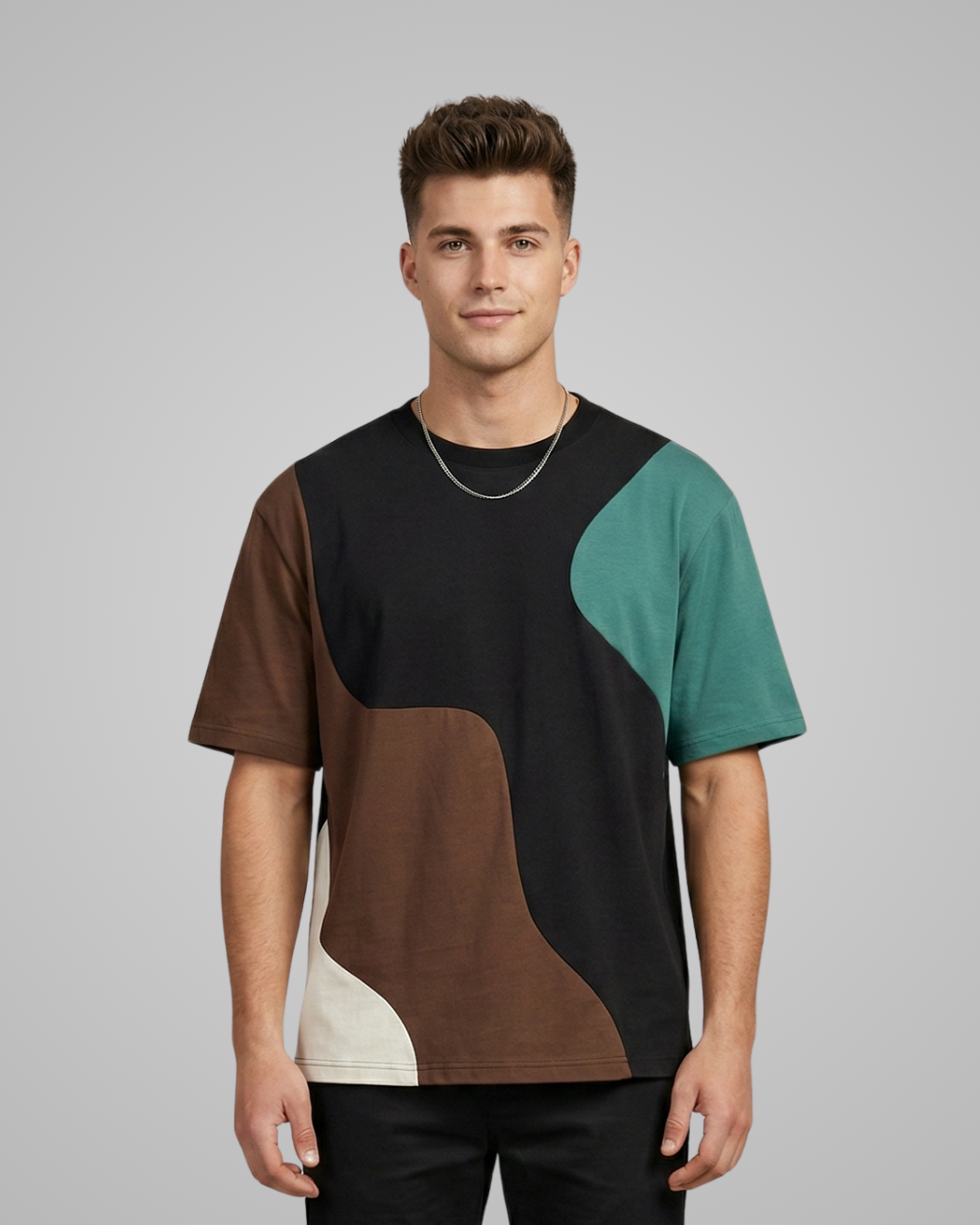 Man wearing a color-blocked t-shirt with black, brown, green, and beige sections on a gray background.