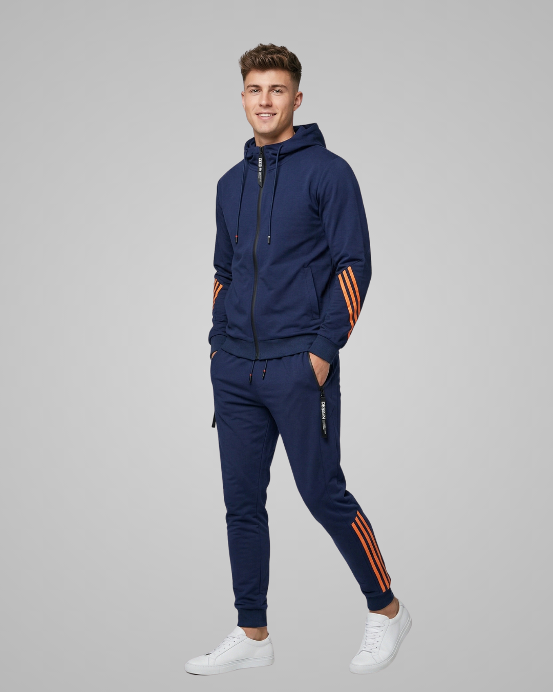 Man wearing a navy tracksuit with orange stripes on a gray background