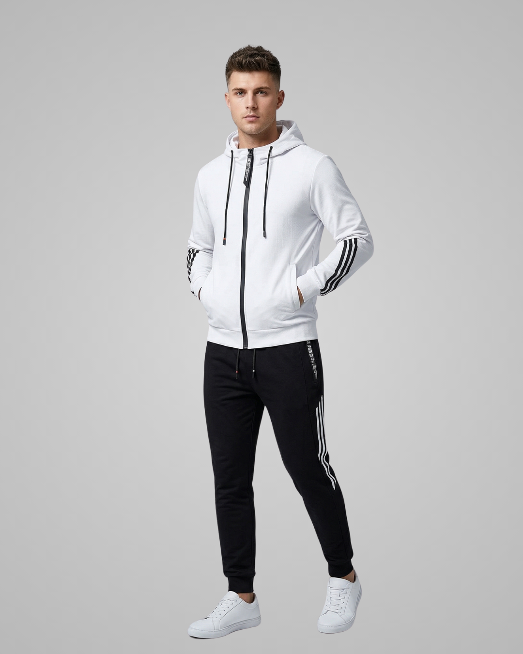 Man wearing a white hoodie and black pants with stripes on a gray background