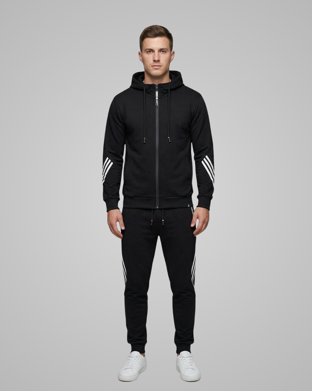 Man wearing a black tracksuit with white stripes on a gray background