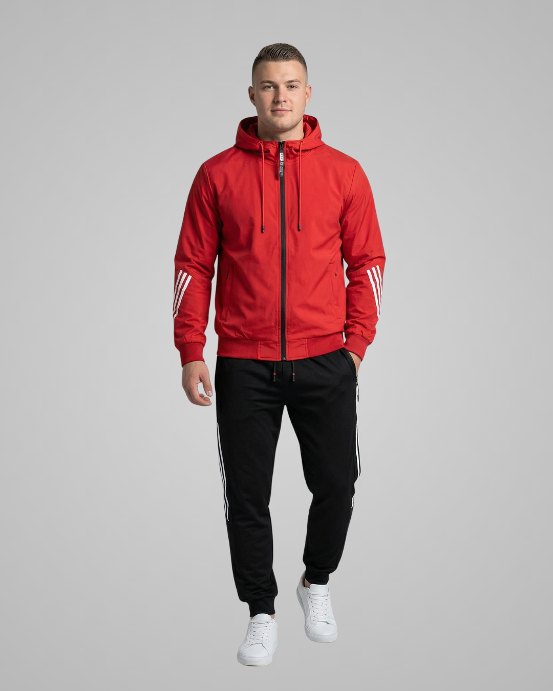 Man wearing a red tracksuit with white stripes on a gray background
