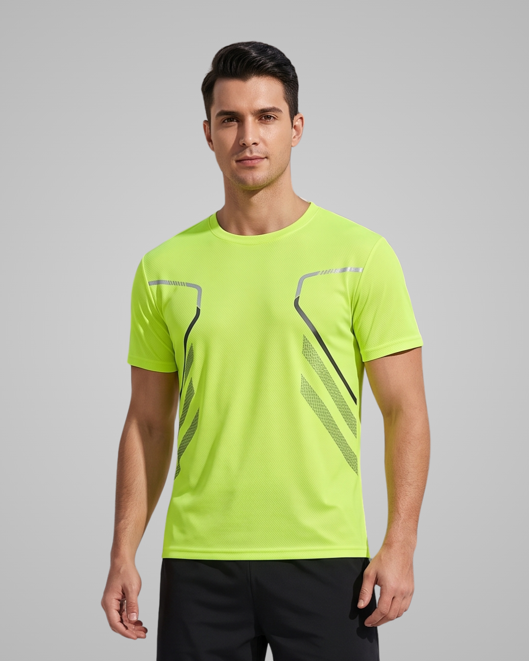 A man wearing a bright neon yellow-green athletic t-shirt with black and gray graphic details on the chest, paired with black athletic pants, against a solid gray studio background.