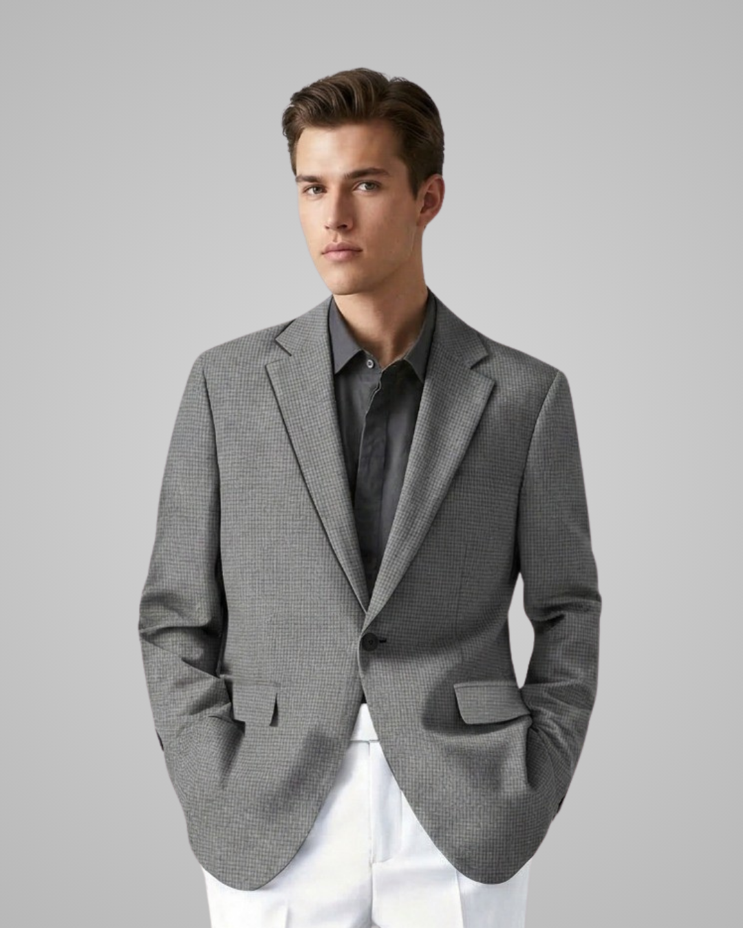 Man wearing a gray blazer over a shirt with white pants on a light gray background