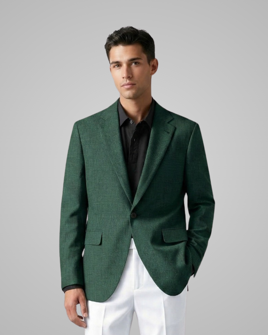 Man wearing a green blazer over a black shirt with white pants on a gray background