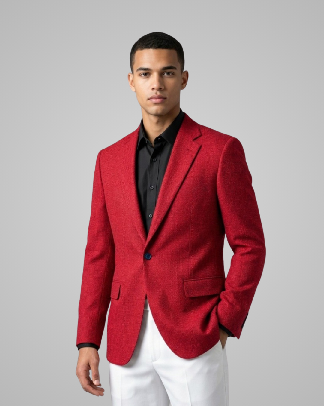 Man wearing a red blazer over a black shirt with white pants on a gray background