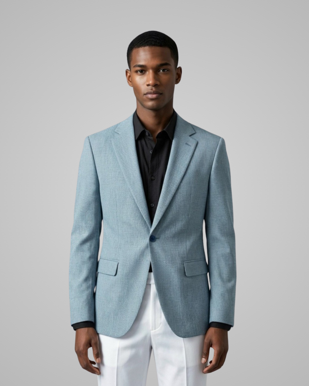 Man wearing a light blue blazer over a black shirt and white pants on a gray background