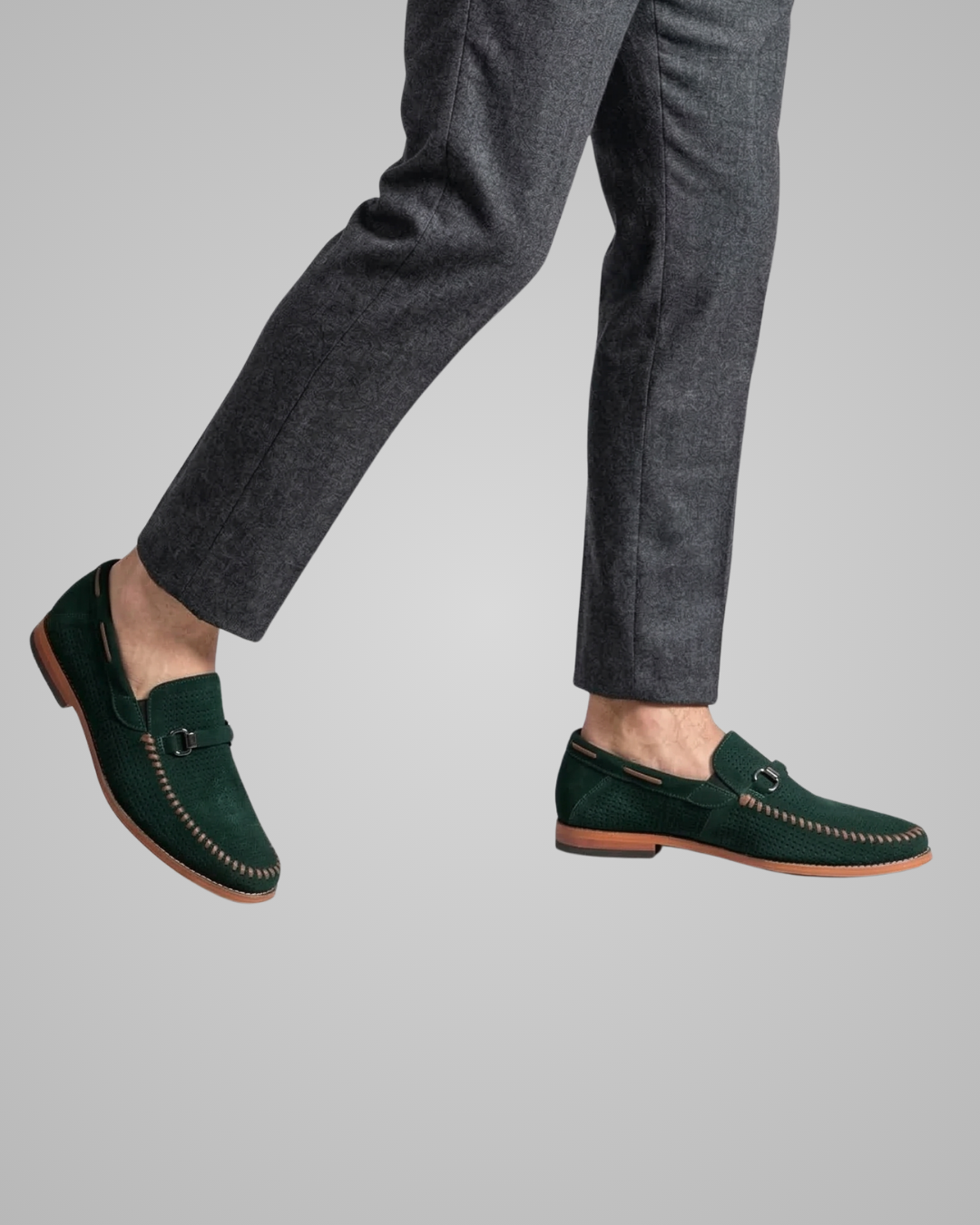 Green loafers worn with gray pants on a plain background