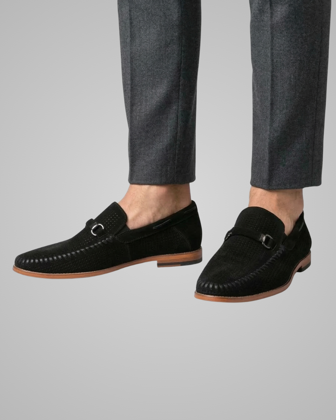 Black loafers worn with gray pants on a light gray background