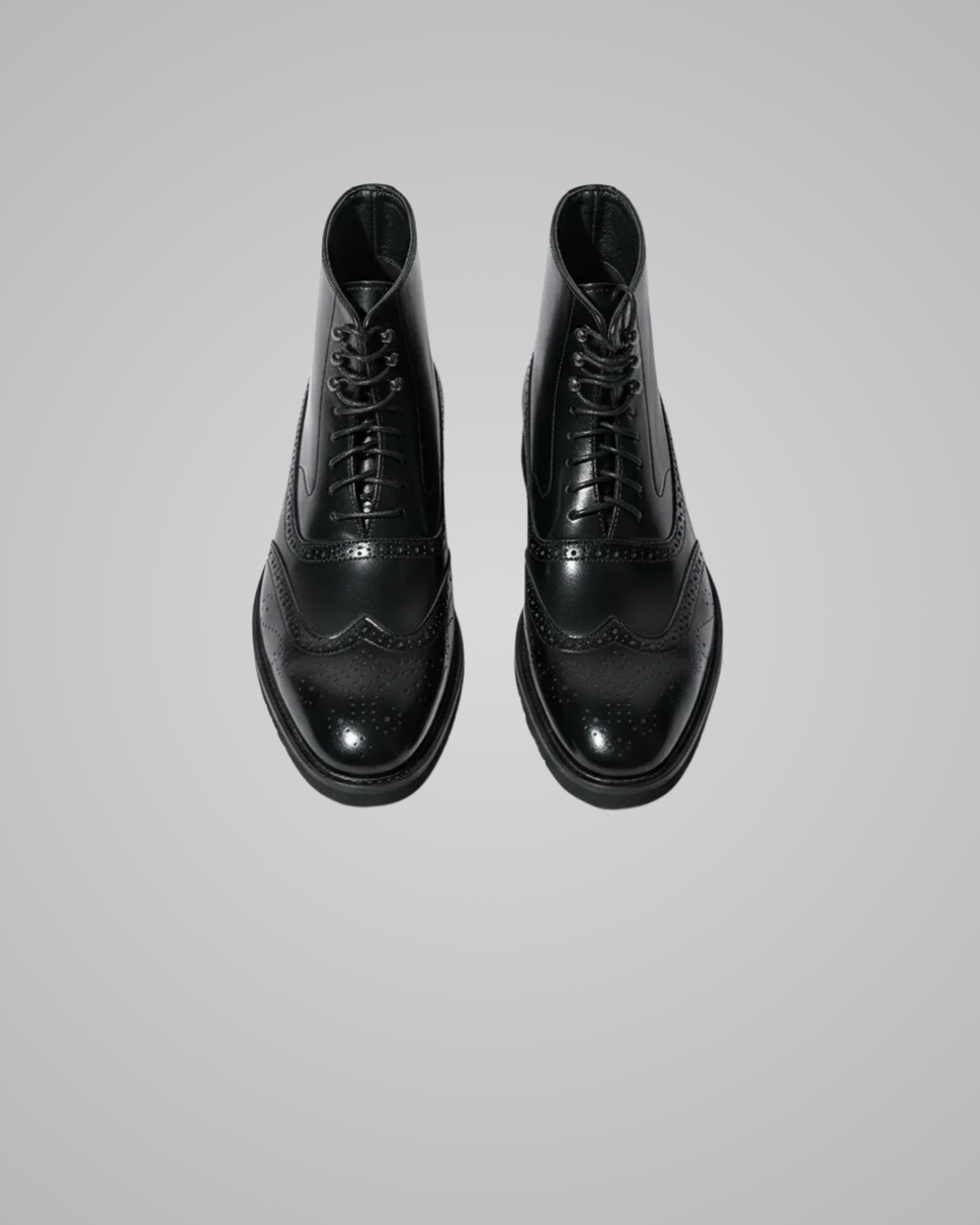 Pair of black leather boots on a light gray background