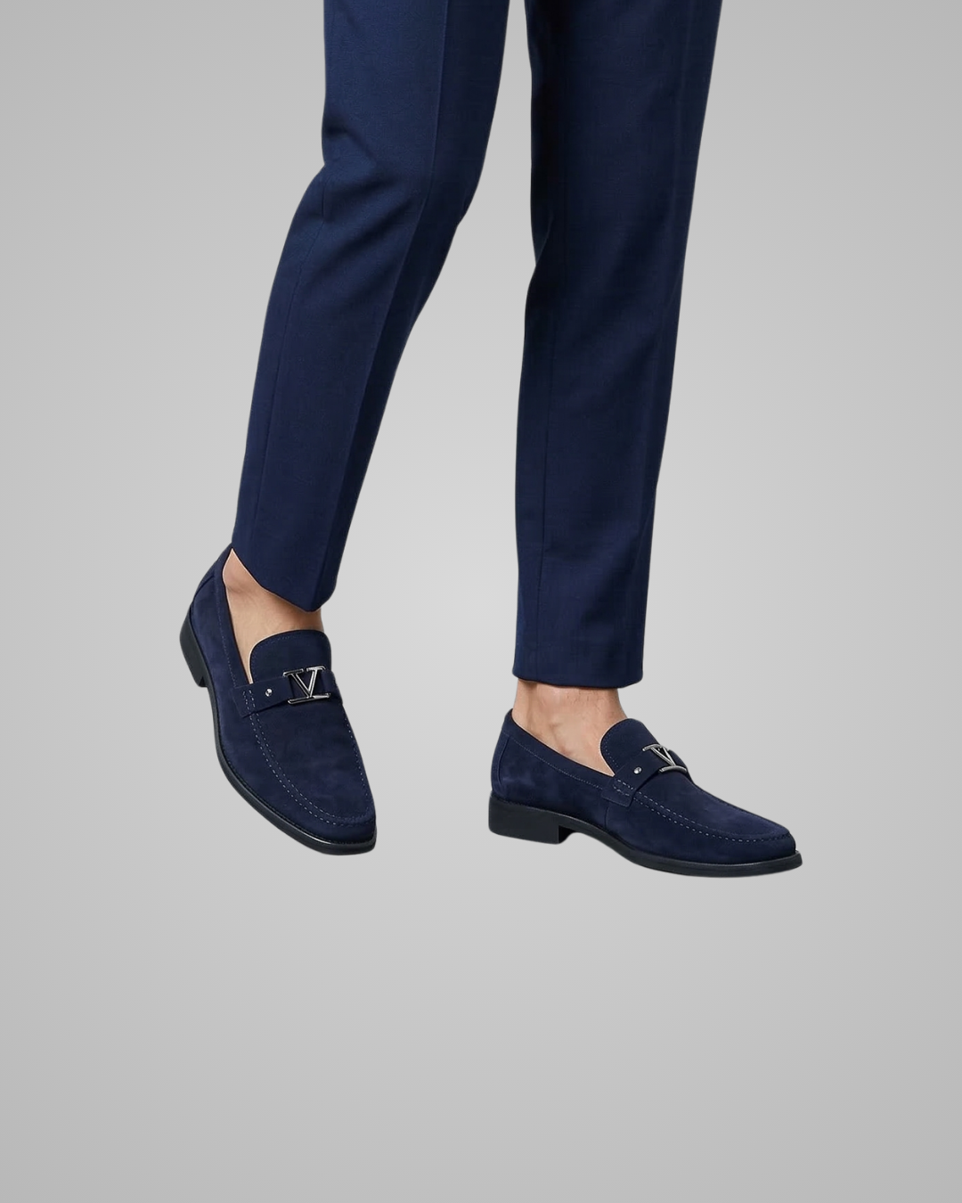 Navy blue loafers worn with navy pants on a gray background