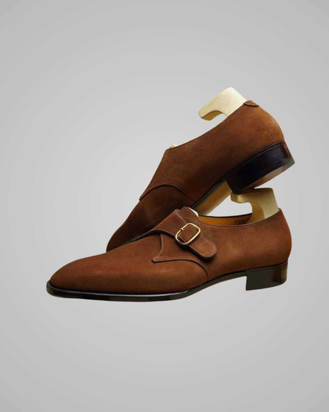 Brown monk strap shoes on a mannequin against a gray background