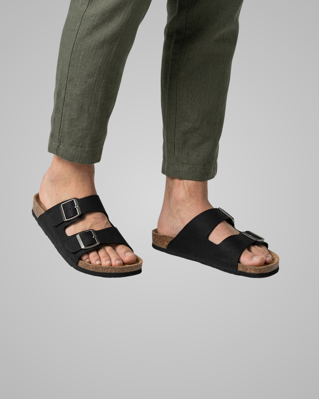 Black sandals worn with green pants on a gray background