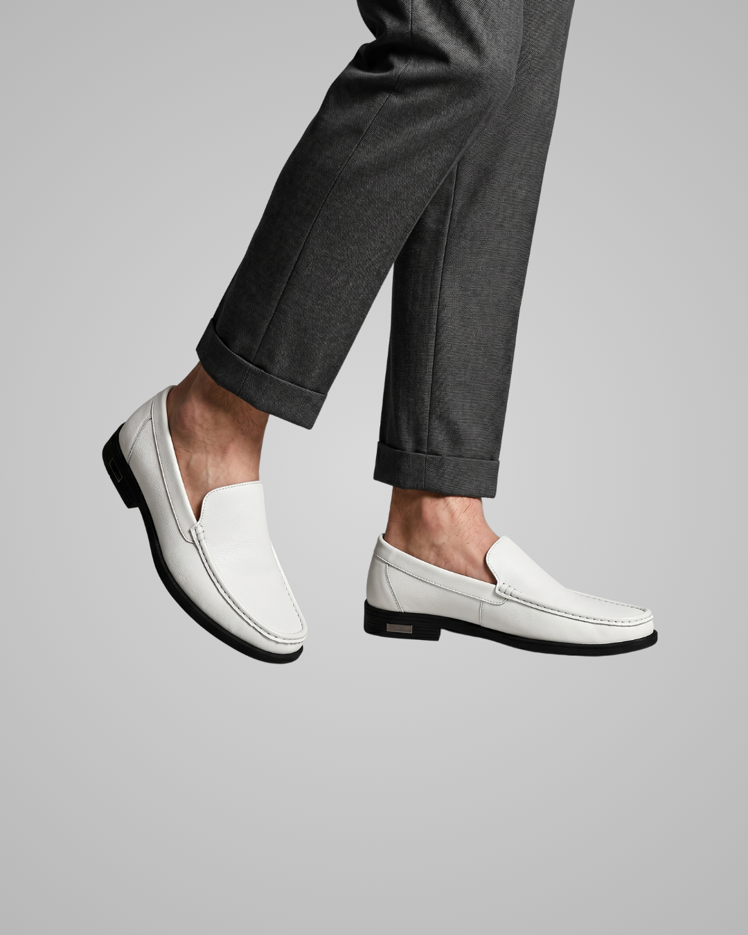 White loafers worn with gray pants on a light gray background