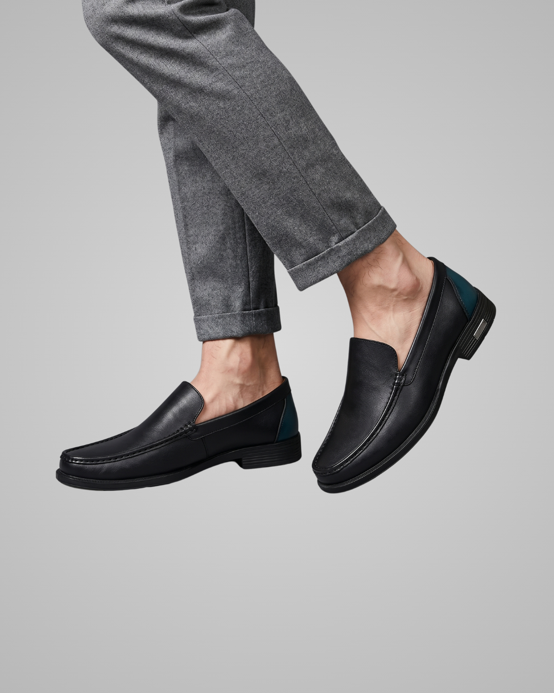Black loafers worn with gray pants on a light gray background