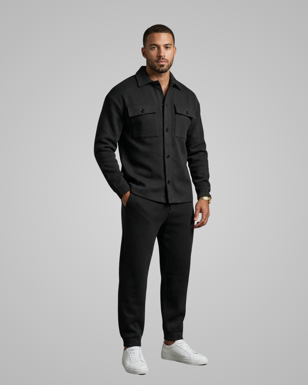 Man wearing a black shirt and pants with white shoes on a gray background