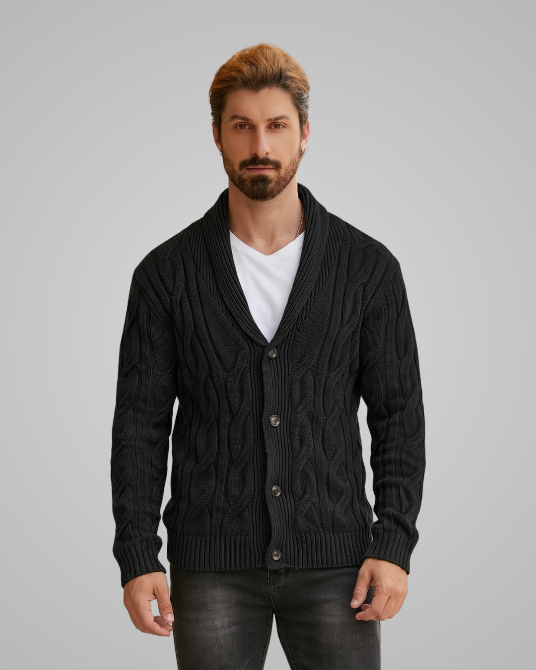 Man wearing a black cable knit cardigan over a white shirt on a gray background