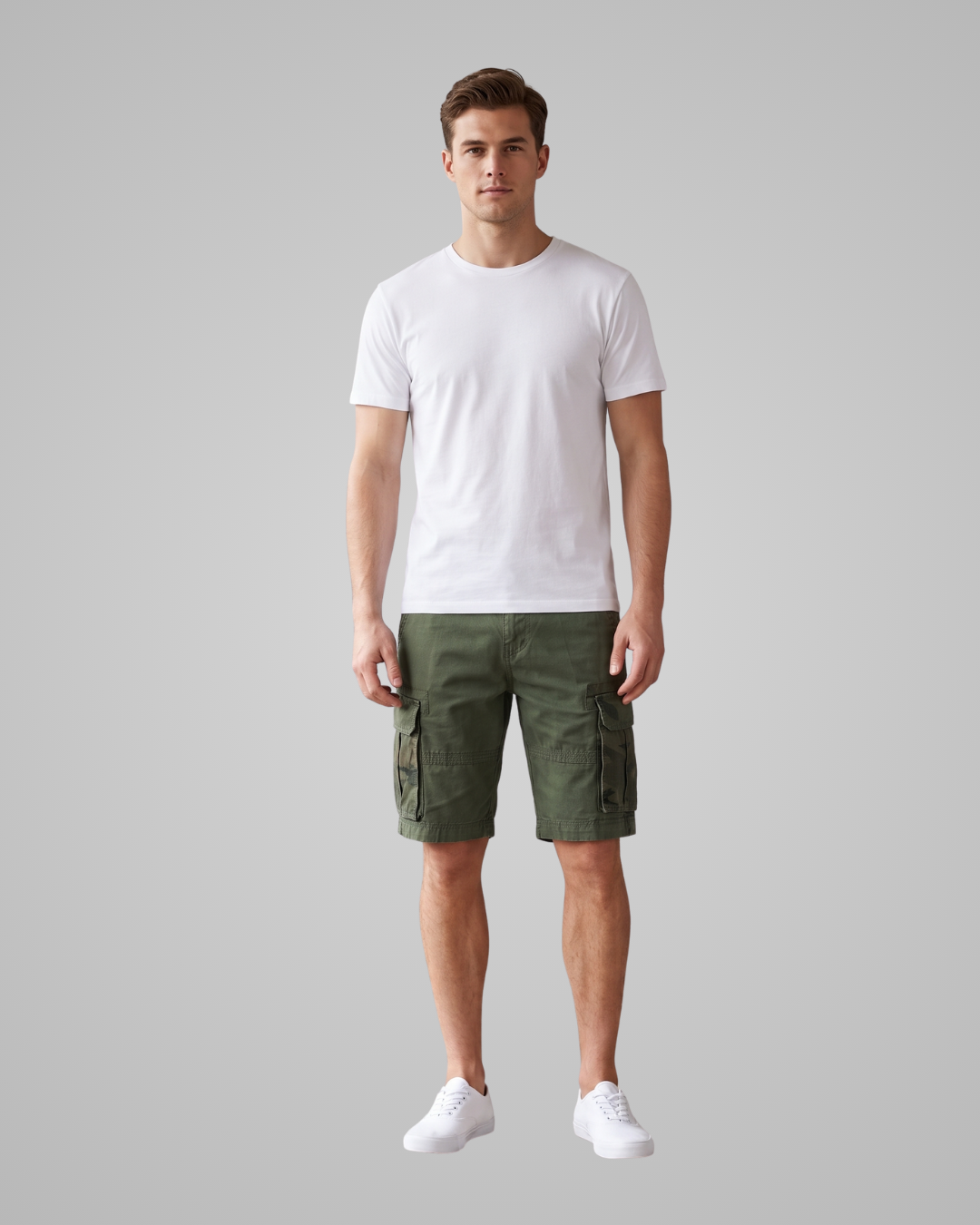 A man modeling a white crew-neck t-shirt and olive green cargo shorts against a solid gray background.