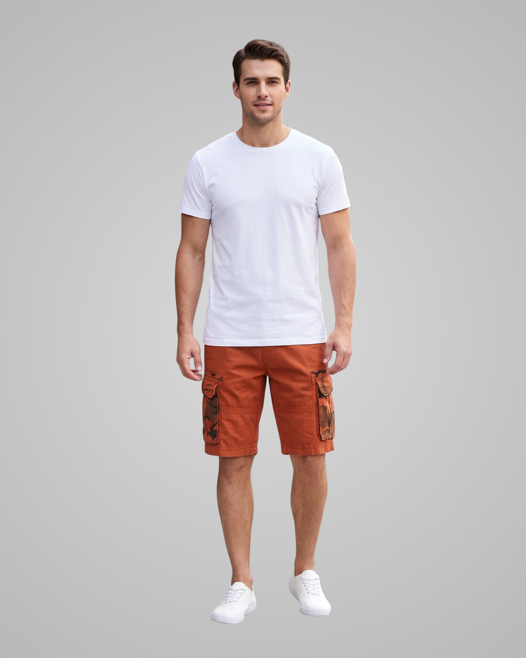 A man modeling a white crew-neck t-shirt and rust-orange cargo shorts against a solid gray background.