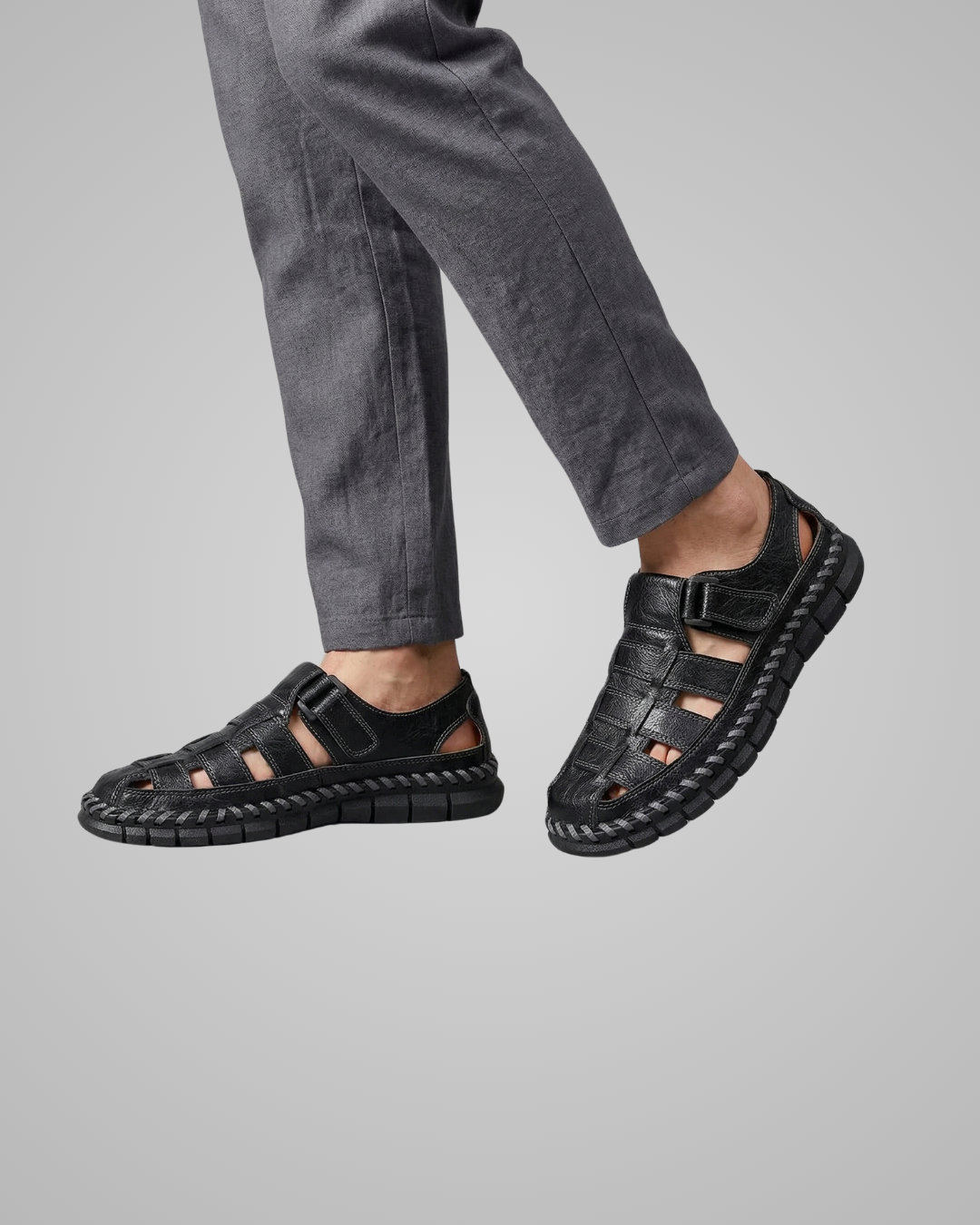 Black sandals worn with gray pants on a light gray background