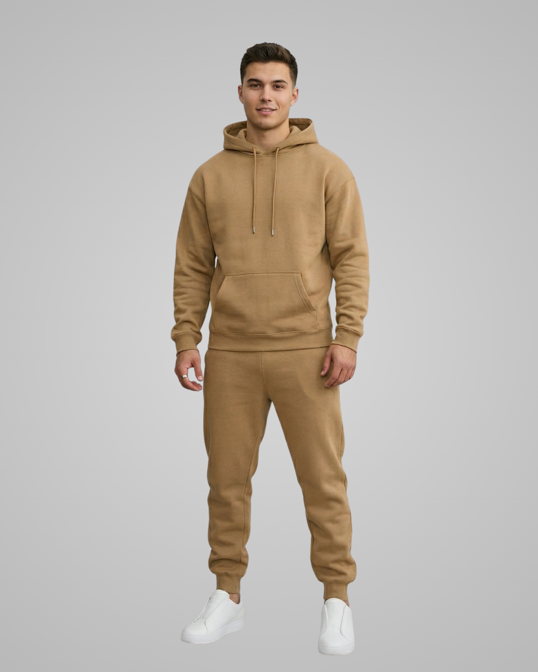 Man wearing a beige hoodie and jogger set on a gray background