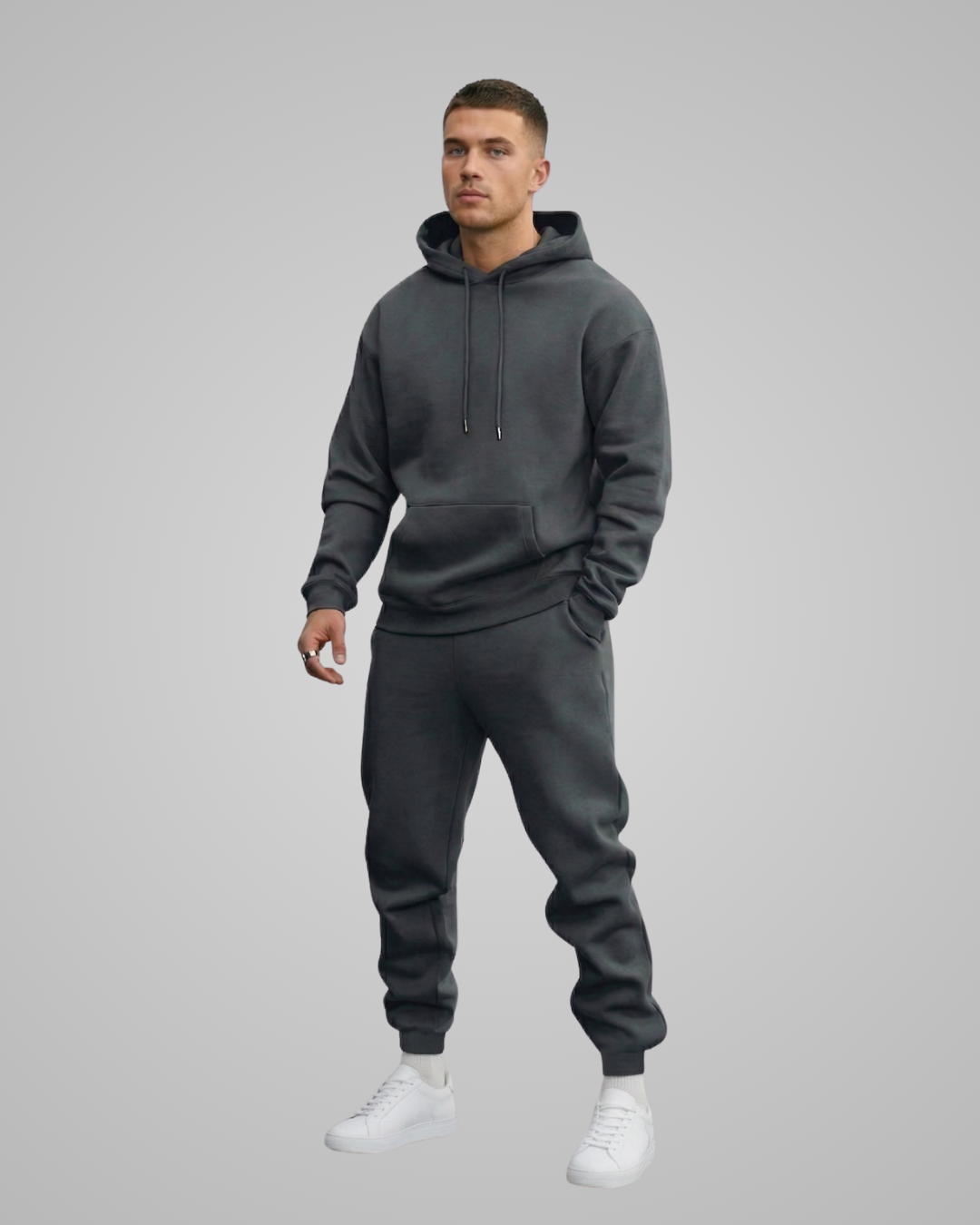 Man wearing a gray hoodie and matching jogger pants on a gray background