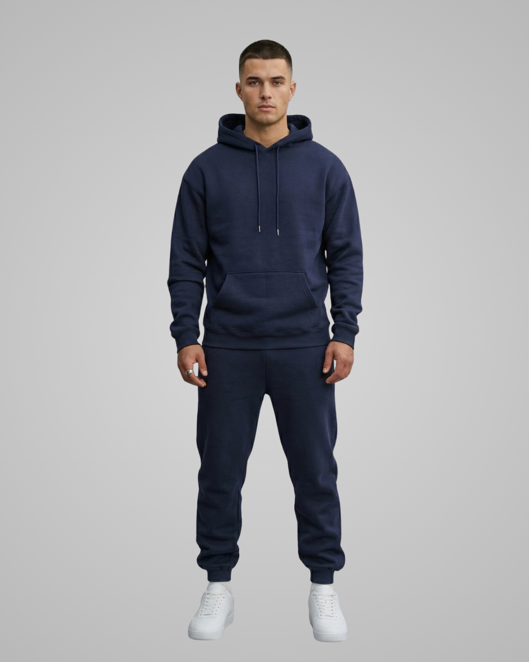 Man wearing a navy blue hoodie and jogger set on a gray background