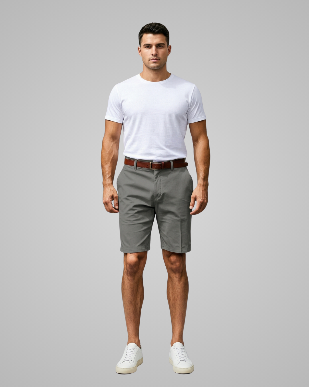 Man wearing a white t-shirt, gray shorts, and white sneakers on a gray background