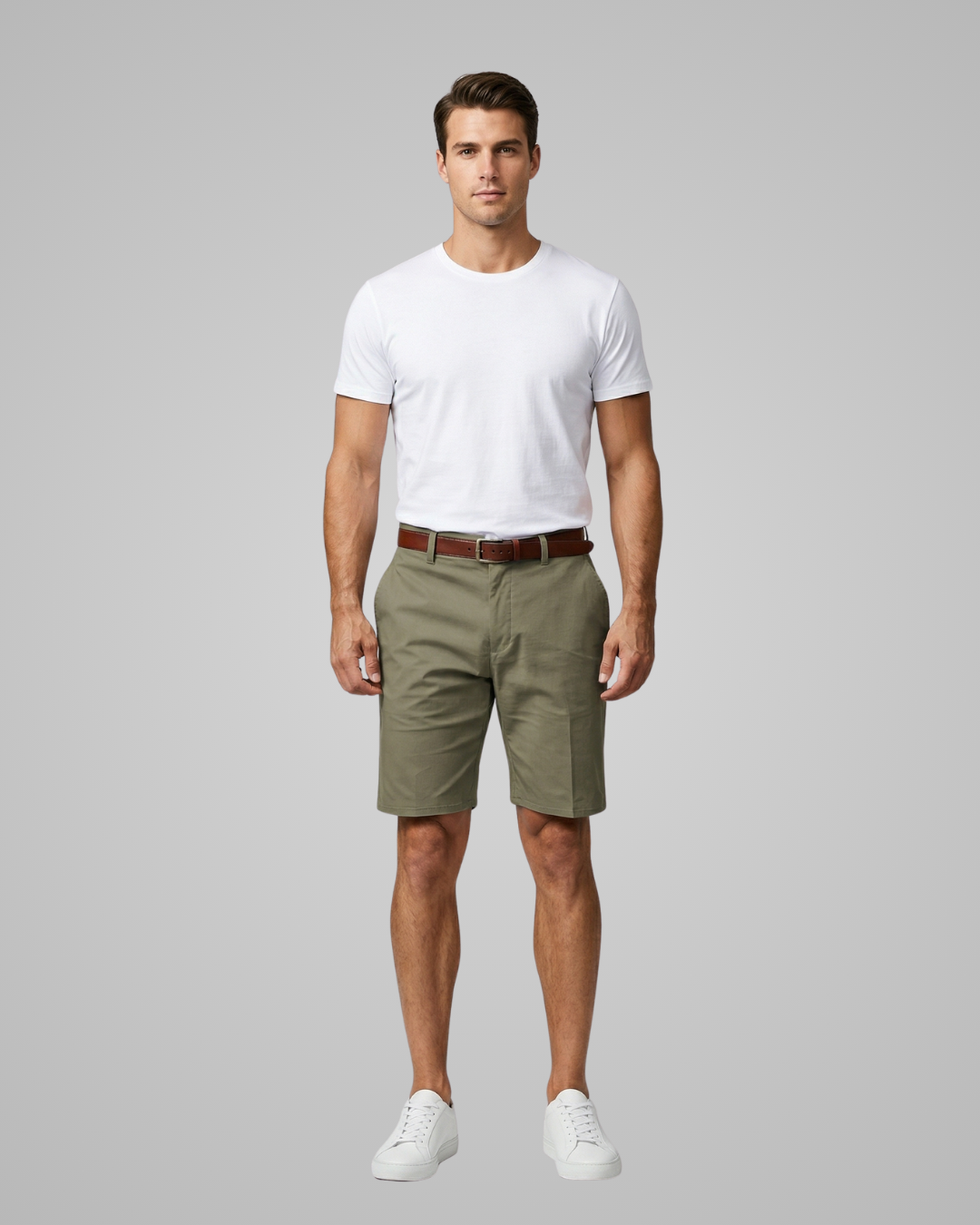 Man wearing a white t-shirt, green shorts, and white sneakers on a gray background
