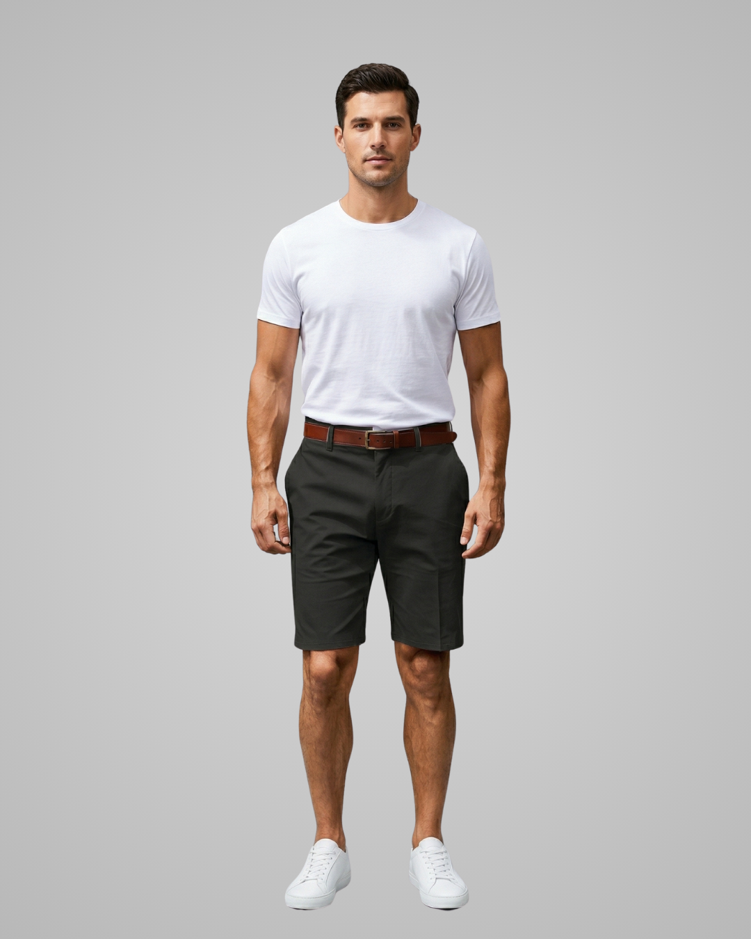 Man wearing a white t-shirt, dark shorts, and white sneakers on a gray background
