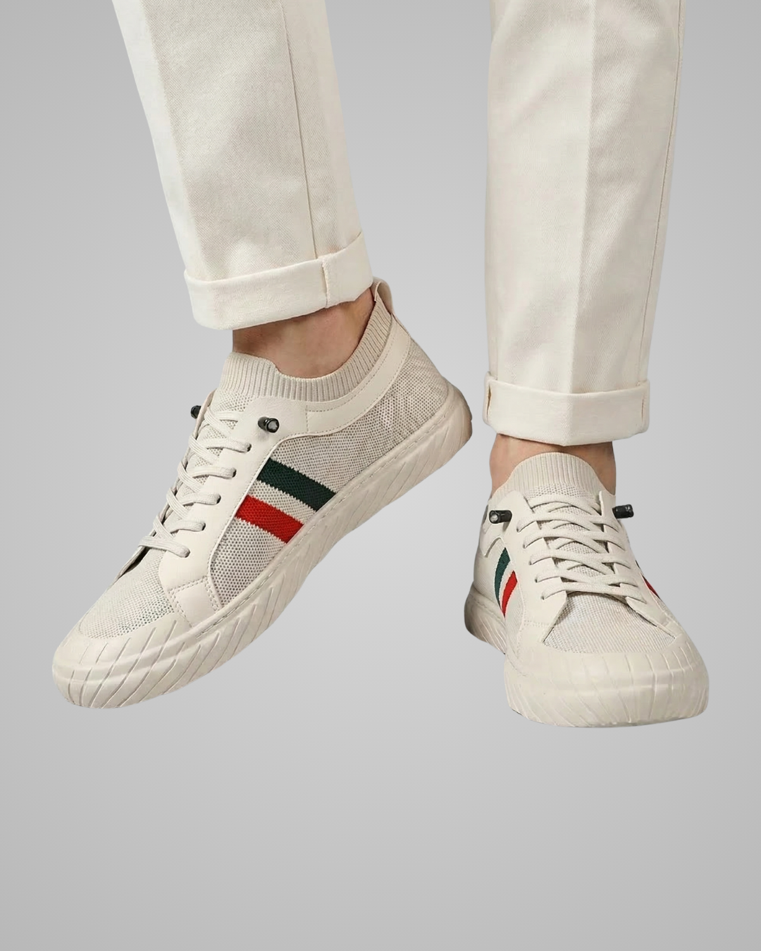 White sneakers with colorful stripes worn with light-colored pants on a gray background